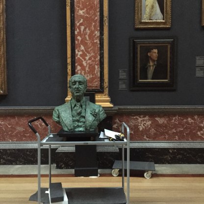 A highlight image for An image of the bust of Louis Colville Gray Clarke by Jacob Epstein being moved in Gallery 1.